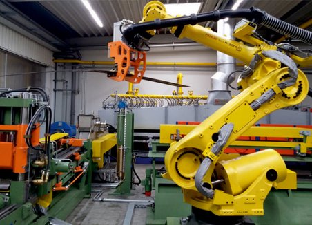 Machine operated robot arm transports a component from one machine to another.
