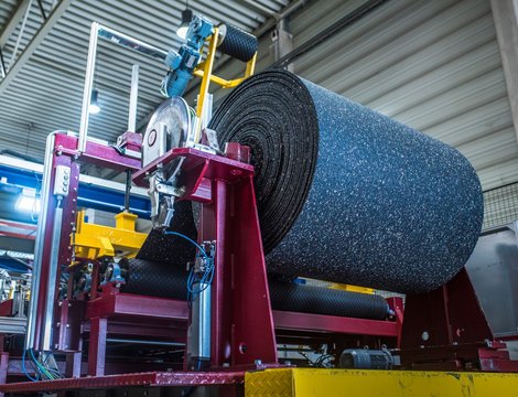 In einer Fabrik werden an einer Maschine große Ballen eines Recycling-Kunststoffes produziert.