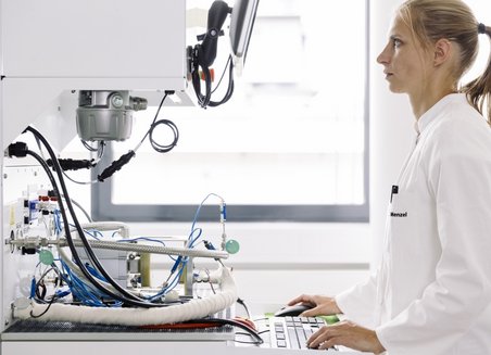 A woman works standing at a computer.